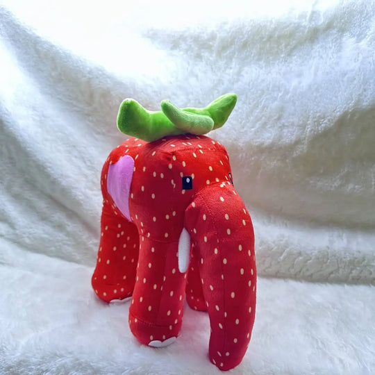 Plush toy shaped like a strawberry with green leaves on a white background