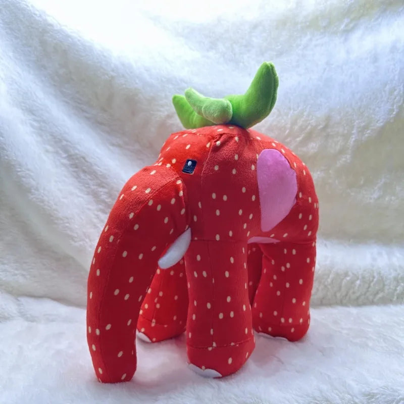 Plush toy shaped like a strawberry with green leaves and a pink heart on a white background