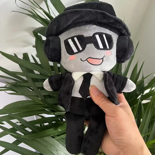 Plush toy with sunglasses and a hat held by a hand against a plant background