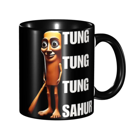 Black ceramic mug featuring a cartoon character with large eyes and an orange body holding a stick, accompanied by the text 'TUNG TUNG TUNG TUNG SAHUR'.