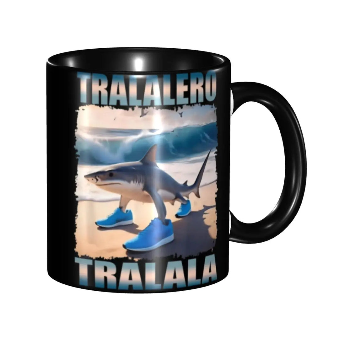 Side view of a black mug featuring a meme‑style design of a beach shark in blue sneakers and the words ‘TRALALERO TRALALA’ in bold letters.