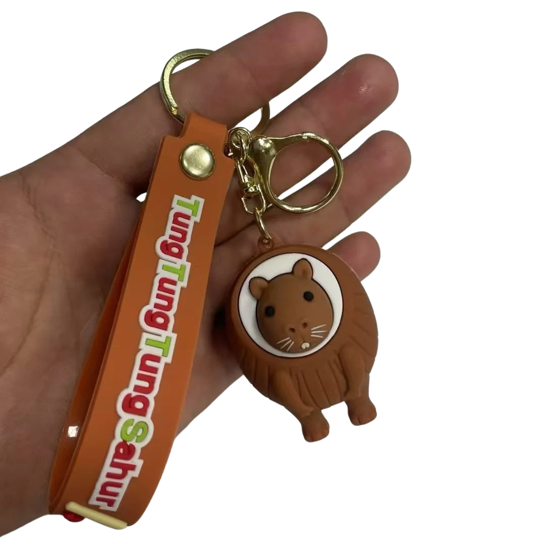 Hand holding a keychain with a cartoon lion design and an orange strap with text.