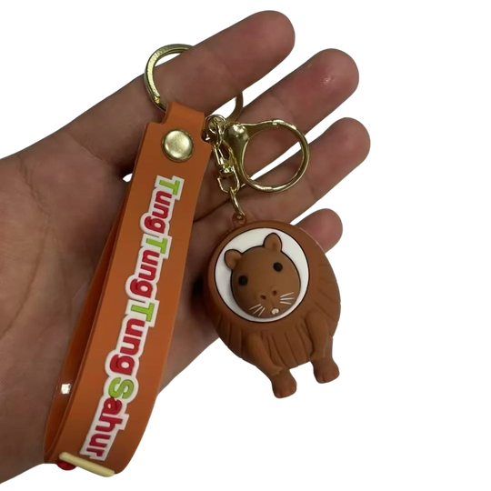 Hand holding a keychain with a cartoon lion design and an orange strap with text.
